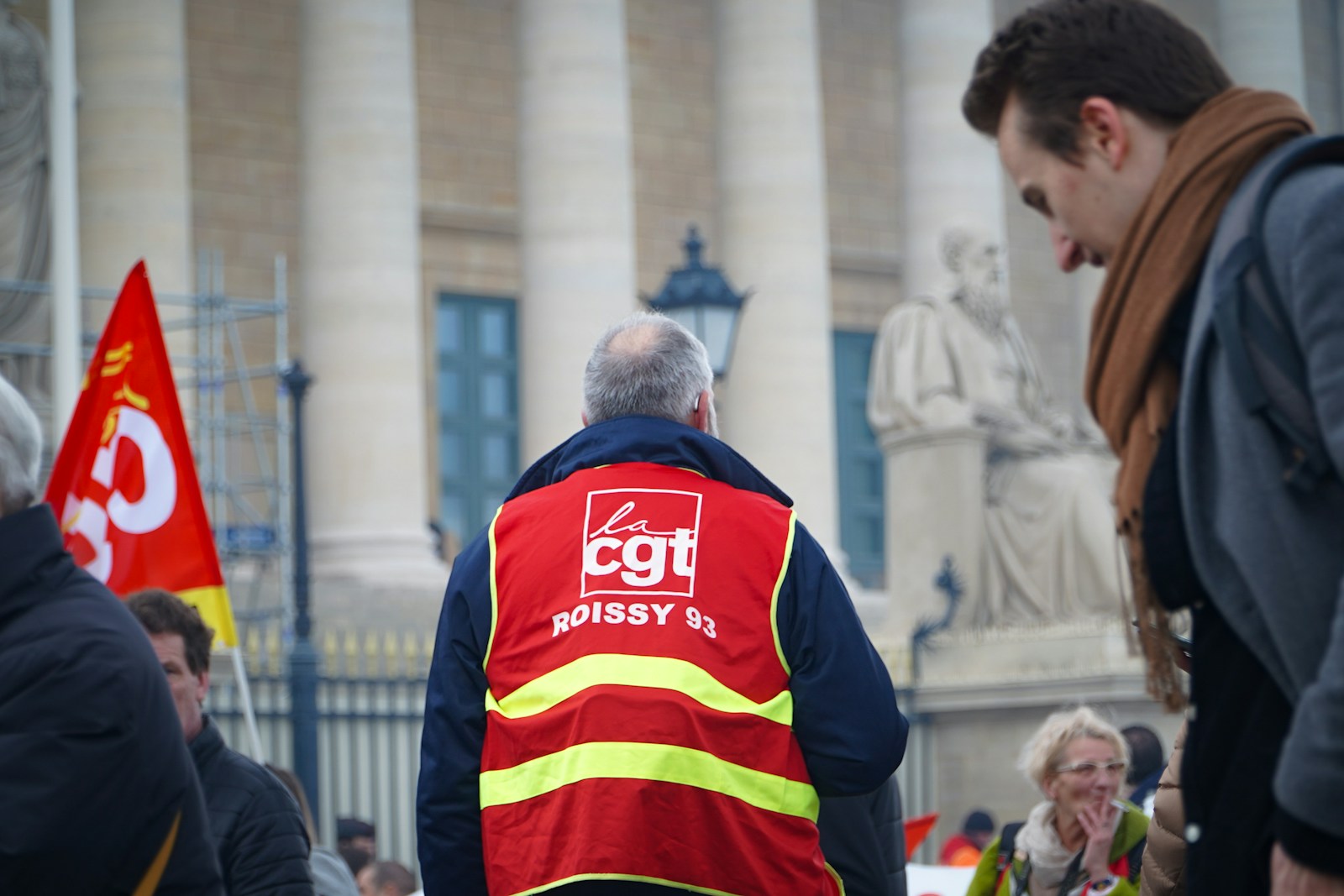 a man in a red vest standing in front of a statue